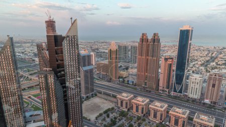 Foto de Edificios de gran altura en Sheikh Zayed Road en Dubai timelapse aéreo por la mañana, Emiratos Árabes Unidos. Rascacielos en el distrito financiero internacional desde arriba durante el amanecer. Paseo por la ciudad casas y villas en el fondo - Imagen libre de derechos