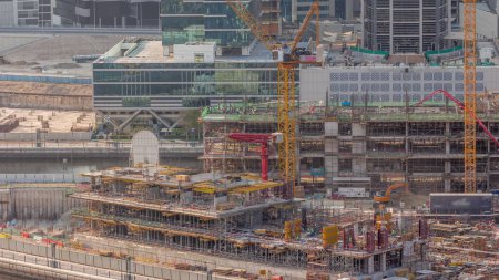 Foto de Gran obra de construcción con muchas grúas de trabajo y timelapse excavadora. Vista aérea superior de gran desarrollo del distrito residencial y de oficinas en Business Bay, Dubai - Imagen libre de derechos