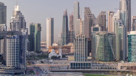 Foto de Paisaje urbano con rascacielos de Dubai Business Bay y timelapse aéreo del canal de agua. skyline moderno con torres residenciales y de oficina en el paseo marítimo. Mezquita rodeada de edificios altos - Imagen libre de derechos