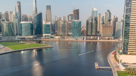 Photo for Aerial view to Dubai Business Bay and Downtown with the various skyscrapers and towers along waterfront reflected in water of canal timelapse. Construction site with cranes - Royalty Free Image