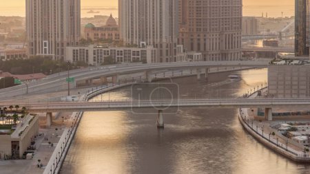 Téléchargez les photos : Promenade à pied le long du canal d'eau dans le quartier Business Bay de Dubaï timelapse aérien pendant le coucher du soleil. Bridges over waterfront with skyscrapers from above, Émirats arabes unis. Lumière chaude orange - en image libre de droit