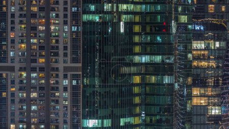 Foto de Edificios de oficinas y residenciales ventanas iluminadas por la noche timelapse. Arquitectura de vidrio, edificio corporativo por la noche con luces brillantes - Imagen libre de derechos