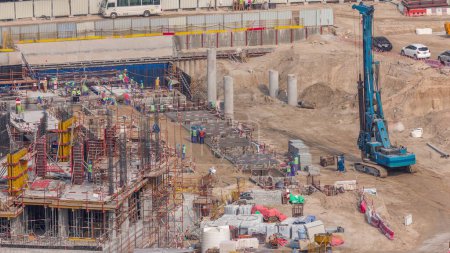 Foto de Gran obra de construcción con muchas grúas de trabajo timelapse. Vista aérea superior de gran desarrollo del distrito residencial y de oficinas en Business Bay, Dubai. Fosa de excavación con pilotes - Imagen libre de derechos