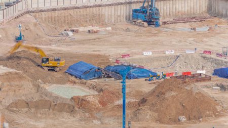 Foto de Conducción de pilotes en foso de cimentación para la construcción del edificio de apartamentos timelapse aéreo. Instalación profunda y excavación con maquinaria pesada como excavadoras, grúas, excavadoras, Dubai - Imagen libre de derechos