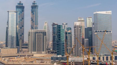 Téléchargez les photos : Paysage urbain avec les gratte-ciel de Dubai Business Bay et le canal d'eau timelapse aérien. Skyline moderne avec tours résidentielles et bureaux. Grues jaunes travaillant sur chantier - en image libre de droit
