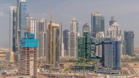 Photo for Cityscape with skyscrapers of Dubai Business Bay and water canal aerial timelapse. Construction site with many cranes. Modern skyline with residential and office towers on waterfront. - Royalty Free Image