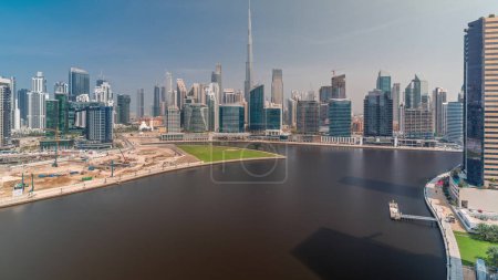 Photo for Aerial panoramic view to Dubai Business Bay and Downtown with the various skyscrapers and towers along waterfront on canal timelapse during all day. Construction site with cranes. Cloudy sky - Royalty Free Image