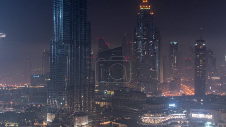 Téléchargez les photos : Vue aérienne de la ville de Dubaï toute la nuit au centre-ville. Skyline futuriste de la ville avec des gratte-ciel éclairés et des tours d'en haut avec des lumières éteintes - en image libre de droit