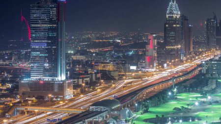 Téléchargez les photos : Vue aérienne de Sheikh Zayed Road à Dubaï Internet City transition jour-nuit. gratte-ciel et circulation sur une autoroute avec station de métro après le coucher du soleil - en image libre de droit