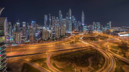 Téléchargez les photos : Panorama du port de plaisance de Dubaï montrant l'intersection des autoroutes nuit de jonction spaghetti. Les gratte-ciel les plus hauts éclairés sur un fond. Vue aérienne du quartier JLT. - en image libre de droit