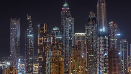 Foto de Rascacielos de Dubai Marina con edificios residenciales más altos iluminados con ventanas brillantes y parpadeantes durante toda la noche. Vista aérea desde el distrito JLT - Imagen libre de derechos