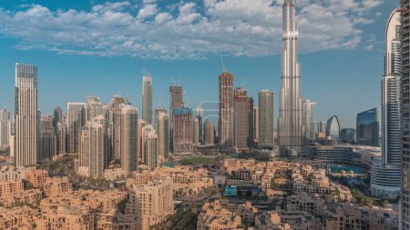 Téléchargez les photos : Dubaï Matin du centre-ville avec le soleil reflété par le plus haut gratte-ciel et d'autres tours vue du haut pendant le lever du soleil, Émirats arabes unis. Maisons traditionnelles de la vieille ville et nuages roses - en image libre de droit