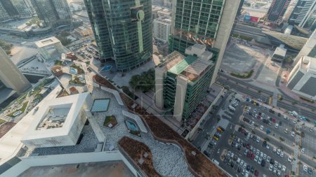 Foto de Rascacielos del centro financiero internacional de Dubai con paseo marítimo y estacionamiento en una antena de la avenida de la puerta durante todo el día. Mirando hacia abajo perspectiva con sombras moviéndose rápido - Imagen libre de derechos