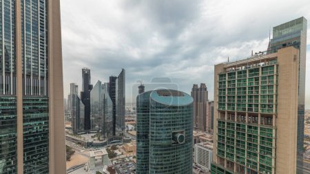 Téléchargez les photos : Panorama montrant les gratte-ciel du centre financier international de Dubaï avec promenade sur une avenue de porte aérienne. Beaucoup de tours de bureaux et de la circulation sur une autoroute. Ciel nuageux - en image libre de droit