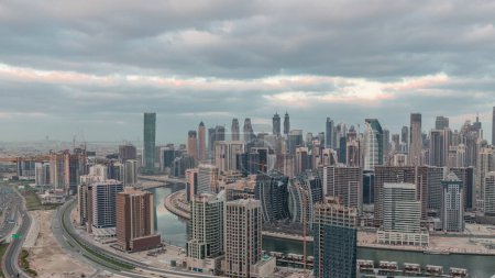 Téléchargez les photos : Skyline avec l'architecture moderne de la baie d'affaires de Dubaï illuminé tours nuit à jour transition. Vue panoramique aérienne avec canal et chantier avant le lever du soleil - en image libre de droit