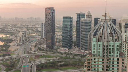 Téléchargez les photos : Un énorme carrefour routier entre le quartier JLT et la marina de Dubaï croisé par l'antenne Sheikh Zayed Road. Terrain de golf près des tours éclairées et des gratte-ciel avec un trafic achalandé - en image libre de droit