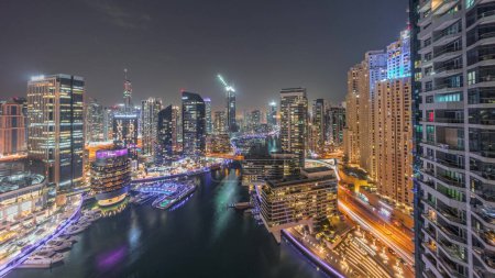 Photo for Aerial panoramic view to Dubai marina skyscrapers around canal with floating boats day to night transition. White boats are parked in yacht club after sunset - Royalty Free Image