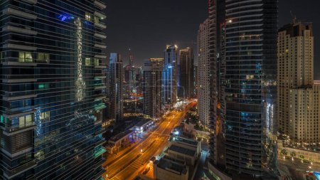 Foto de Vista aérea panorámica de la Marina de Dubai y la zona de JBR y el tráfico en la carretera durante toda la noche. Con rascacielos iluminados y luces apagadas - Imagen libre de derechos