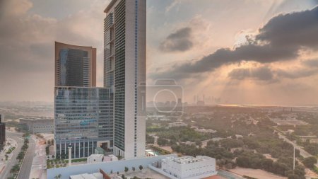 Foto de Salida del sol en el distrito financiero internacional de Dubai transición. Vista aérea de las torres de oficinas de negocios por la mañana. Rascacielos con hoteles cerca del centro - Imagen libre de derechos