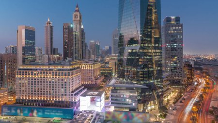 Foto de Distrito financiero internacional de Dubái transición día a noche. Vista aérea de las torres de oficinas de negocios después del atardecer. Rascacielos con hoteles y centros comerciales cerca del centro - Imagen libre de derechos