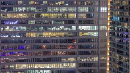 Foto de Ventanas de edificios de oficinas transición día a noche, la luz de las ventanas de los rascacielos. Paisaje nocturno de la ciudad con espacio de trabajo resplandeciente - Imagen libre de derechos