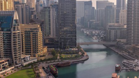 Photo for Dubai Marina with boats and yachts parked in harbor and skyscrapers around canal aerial morning during sunrise. Towers along waterfront with warm light - Royalty Free Image