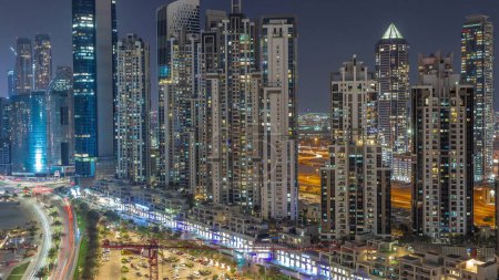 Téléchargez les photos : Bay Avenue avec des tours modernes développement résidentiel dans Business Bay transition aérienne de jour à la nuit, Dubaï, EAU. Gratte-ciel après le coucher du soleil - en image libre de droit
