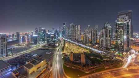 Photo for Panorama of Bay Avenue with modern towers residential development in Business Bay aerial day to night transition, Dubai, UAE. Skyscrapers with traffic on a road near big parking lot - Royalty Free Image