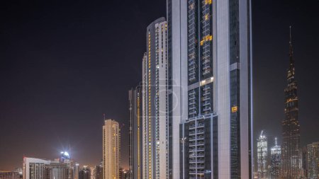 Foto de Los rascacielos más altos del centro de dubai y la bahía de negocios se encuentran en la calle Bouleward cerca de la antena del centro comercial durante toda la noche y el amanecer. Iluminación y luces apagadas - Imagen libre de derechos