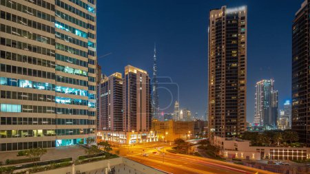 Photo for Aerial panoramic view to Dubai downtown and difc skyscrapers with busy traffic on intersection in Business bay district day to night transition after sunset. - Royalty Free Image