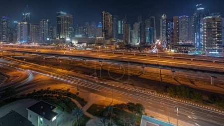 Téléchargez les photos : Panorama montrant Dubai Marina plus haut bloc de gratte-ciel nuit. Vue aérienne du quartier JLT vers les immeubles à appartements, les hôtels et les tours de bureaux près de l'autoroute. - en image libre de droit