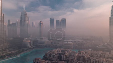 Téléchargez les photos : Vue aérienne Le brouillard matinal couvrait le quartier du Dubai International Financial Centre. Tours de bureaux et hôtels avec gratte-ciel et centre commercial modernes au lever du soleil - en image libre de droit