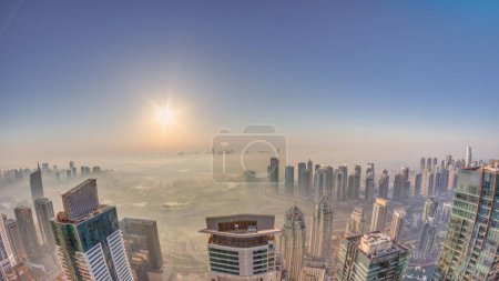 Photo for Panorama of Dubai Marina with JLT skyscrapers and golf course during sunrise, Dubai, United Arab Emirates. Aerial view from above towers foggy morning. City skyline with rooftops - Royalty Free Image