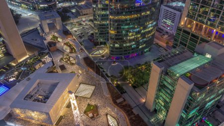 Foto de Dubai centro financiero internacional rascacielos y paseo marítimo en una avenida de la puerta día aéreo a la transición nocturna. Torres iluminadas y mezquita miran hacia abajo desde arriba - Imagen libre de derechos
