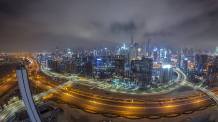 Foto de Skyline panorámico de Dubai con la bahía de negocios y el centro de distrito durante toda la noche. Vista aérea de gran angular de muchos rascacielos modernos y tráfico ocupado en la carretera al khail. Emiratos Árabes Unidos. - Imagen libre de derechos