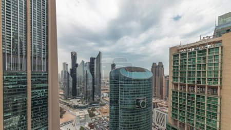 Foto de Panorama que muestra los rascacielos del centro financiero internacional de Dubai con paseo marítimo en una antena de la avenida de la puerta. Muchas torres de oficinas y el tráfico en una carretera. Cielo nublado - Imagen libre de derechos
