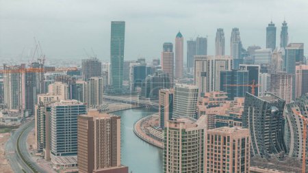 Téléchargez les photos : Skyline avec l'architecture moderne de la baie d'affaires de Dubaï illuminé tours nuit à jour transition. Vue aérienne avec canal et chantier avant le lever du soleil - en image libre de droit