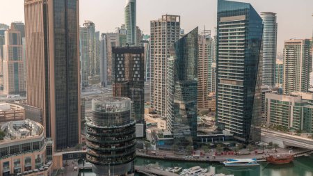 Photo for Dubai Marina Skyline with JLT district skyscrapers on a background aerial. Towers with glass surface and waterfront with yachts during sunrise - Royalty Free Image