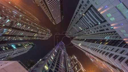 Téléchargez les photos : Regardez vers le ciel nocturne avec les plus hauts gratte-ciel avec des fenêtres éclairées. Perspective grand angle de la jungle urbaine dans la marina de Dubaï - en image libre de droit