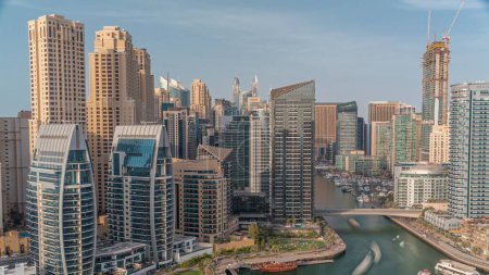Téléchargez les photos : Dubai Marina avec plusieurs bateaux et yachts garés dans le port et gratte-ciel autour du canal aérien. Tours du quartier JBR avec des ombres se déplaçant rapidement - en image libre de droit