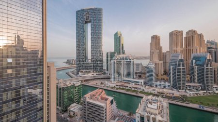 Foto de Dubai Marina rascacielos y el distrito JBR antes del amanecer con edificios de lujo iluminados y resorts aéreos noche a día transición. Frente al mar con palmeras y barcos flotando en el canal - Imagen libre de derechos
