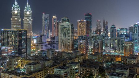Foto de Rascacielos en el distrito de Barsha Heights y edificios de poca altura en el distrito de Greens transición aérea día a noche. Dubai skyline con torres de la ciudad de Internet - Imagen libre de derechos