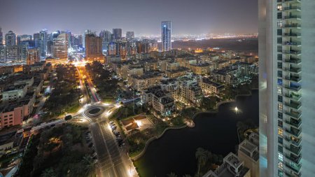 Téléchargez les photos : Panorama montrant des gratte-ciel dans le quartier de Barsha Heights et des bâtiments de faible hauteur dans la nuit aérienne du quartier des Verts. Skyline de Dubaï avec palmiers et arbres - en image libre de droit