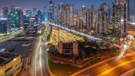 Téléchargez les photos : Bay Avenue avec des tours modernes développement résidentiel à Business Bay panoramique aérienne jour à nuit transition, Dubaï, Émirats arabes unis. gratte-ciel avec circulation sur une route près d'un grand parking - en image libre de droit