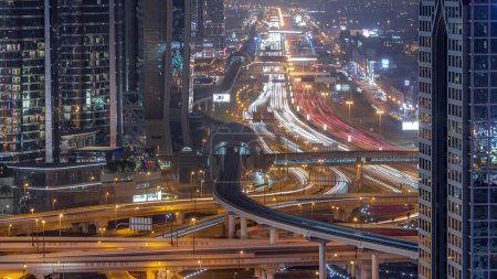 Foto de Ocupado Sheikh Zayed Road día aéreo a la transición nocturna, metro y rascacielos modernos en la lujosa ciudad de Dubái. Tráfico pesado en una carretera con muchos coches. Emiratos Árabes Unidos - Imagen libre de derechos