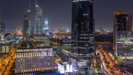 Foto de Vista aérea del Distrito Financiero Internacional de Dubái con muchos rascacielos de transición día a noche después del atardecer. Tráfico en una carretera cerca de avenida comercial y torres de oficinas. Dubai, Emiratos Árabes Unidos. - Imagen libre de derechos