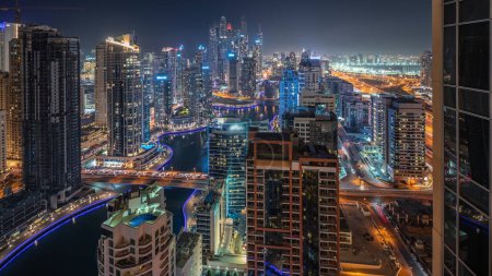 Téléchargez les photos : Panorama showing various skyscrapers in tallest recidential block in Dubai Marina and JDR district aerial night with artificial canal. Many towers and yachts - en image libre de droit