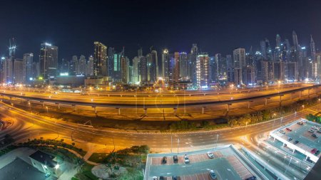 Téléchargez les photos : Panorama des gratte-ciel de Dubai Marina et de la route Cheikh Zayed avec métro aérien pendant toute la nuit. Trafic sur une autoroute près des tours modernes, Émirats arabes unis - en image libre de droit