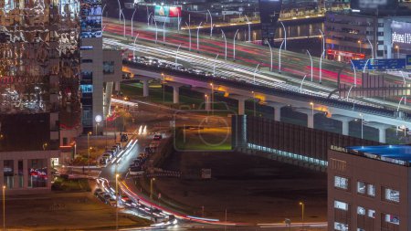 Téléchargez les photos : Vue aérienne de l'intersection de la route animée Cheikh zayed et les jonctions de la circulation dans la ville de Dubaï timelapse de nuit. Construction moderne carrefour et autoroutes pour éviter les embouteillages. Beaucoup de voitures de conduite - en image libre de droit