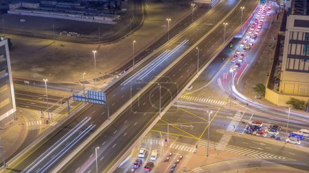 Téléchargez les photos : Vue aérienne de l'intersection de la route achalandée et des carrefours routiers dans la ville de Dubaï la nuit timelapse. Construction moderne de carrefours et d'autoroutes pour éviter les embouteillages. Beaucoup de voitures de conduite - en image libre de droit